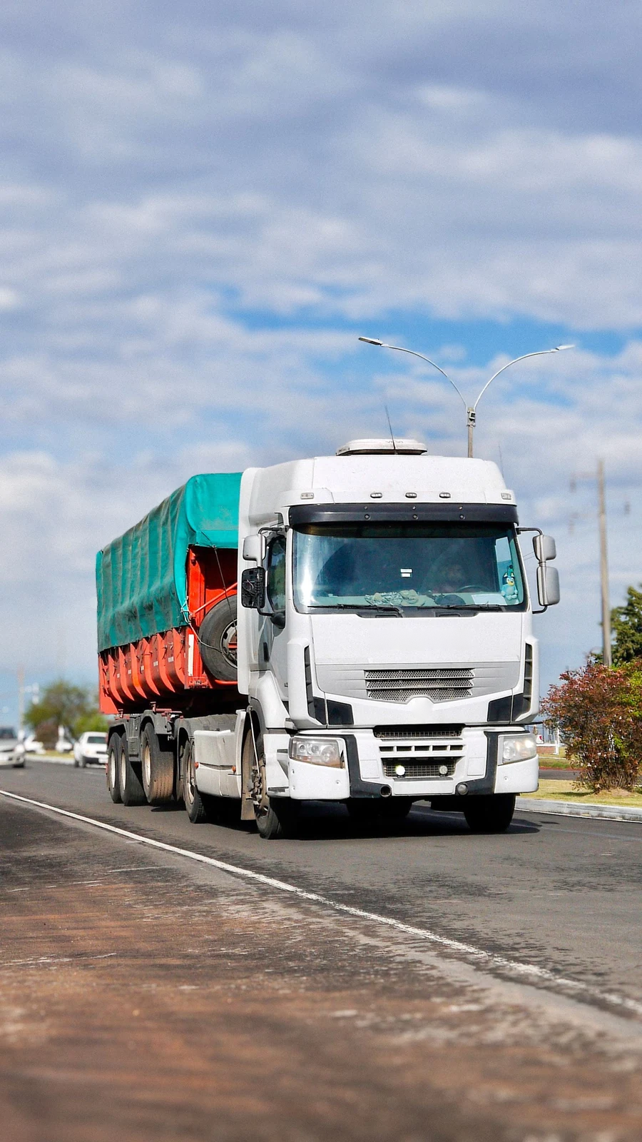 European cab-over tractor hauling a loaded trailer on a highway