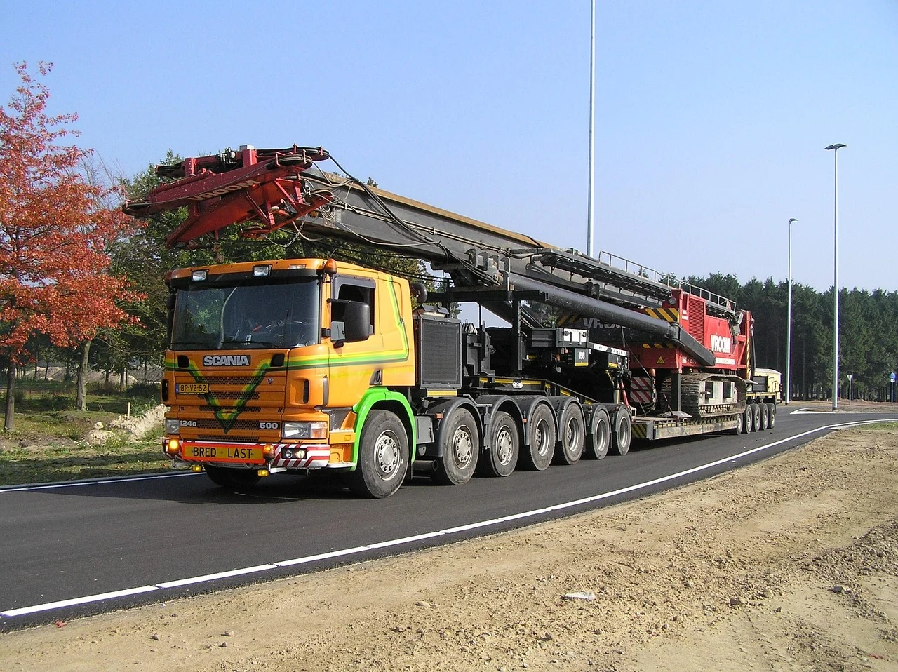 European Scania cab-over tractor hauling heavy crane equipment on a multi-axle low-loader